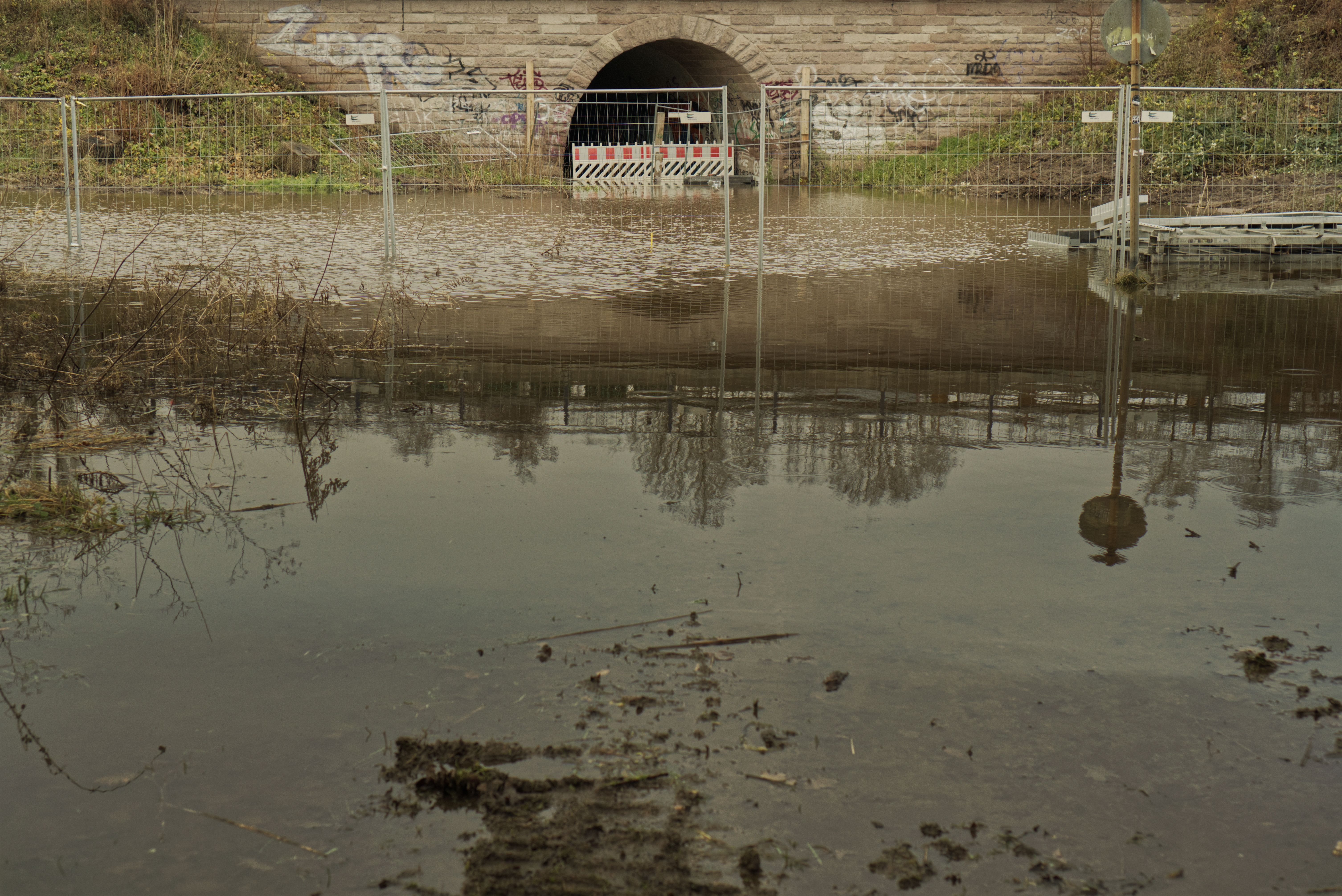 An archway near Maschsee is flooded with a half-submerged construction fence closing it off